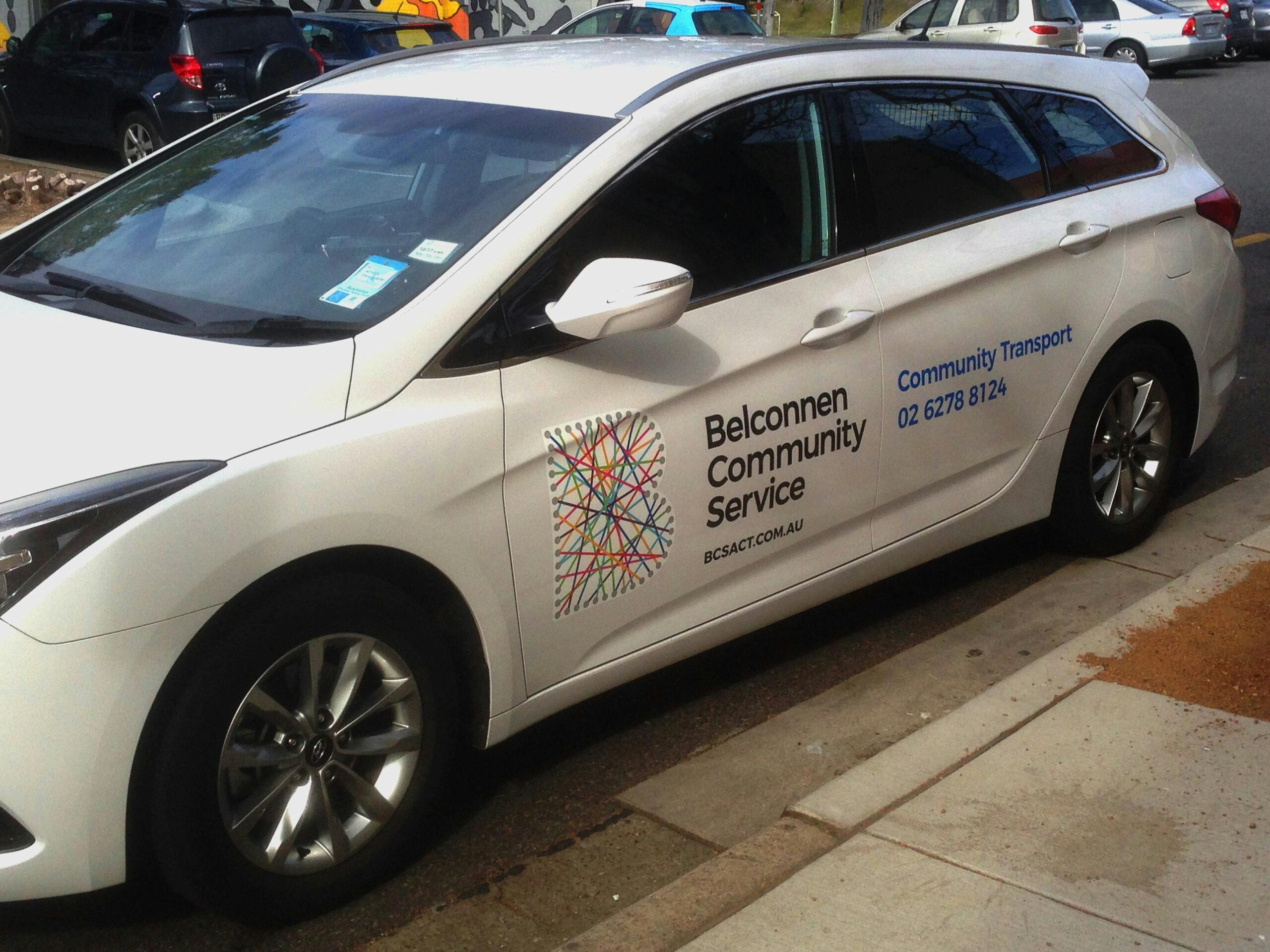 A photo of a CRCS transport vehicle parked on the side of a curb, the car is white.