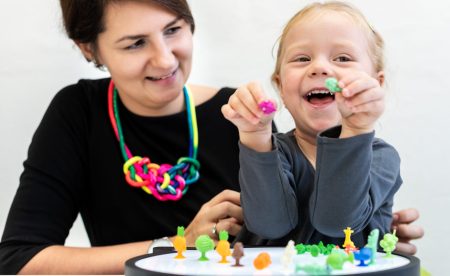 Toddler girl in child occupational therapy session doing sensory playful exercises with her therapist.