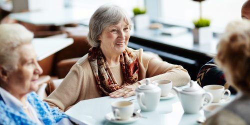 Senior woman sitting in cafe with friends
