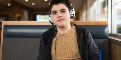 Teen boy with head phones on sits in booth at restaurant