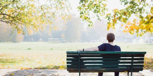 Young man relaxing on park bench on a autumn day