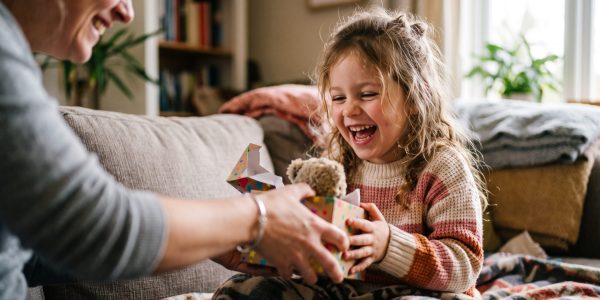 A Daughter's Delight: A joyous little girl, with a radiant smile and infectious laughter, receives a special gift from her mother, creating a heartwarming moment of connection and love.